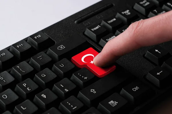 Pressing enter button with Turkish flag, represents a cyber-attack of Turkey, metaphor of learning Turkish language, black keyboard close up, front view, selective focus