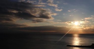 Geniş açılı gün batımı ufuk çizgisi, 4K gün batımı ve dalga, bulutlu gökyüzü, koyda yürüyen insanlar, yumuşak ışıkla hareket eden bulutlar, gün batımı ve deniz kavramı, doğa fikri.