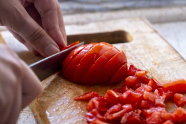 Erkek eli domatesi tahta tahtada dilimler, hazırlar ve pişirir, salata fikri yapar, domates keser veya doğrar, mutfakta yemek yapar, bıçak kullanır.