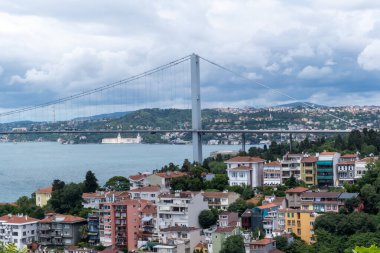 İstanbul Boğazı ile Marmara köprüsü ve deniz kıyısındaki renkli binalar, mavi deniz ve bulutlu gökyüzü, Boğaz kablolu köprüsü, İstanbul 'daki şehir manzarası görüntüleri, Asya ve Avrupa' nın bağlantısı