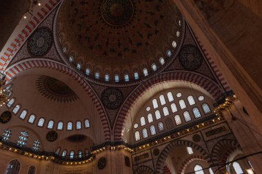 Süleyman Camii 'nin içi, camide yeşil plaka üzerine İslami metin, geçmişe dönük altın avize, İslam ve din kavramına yakın, seçici odak: Süleyman Camii, İstanbul, Türkiye