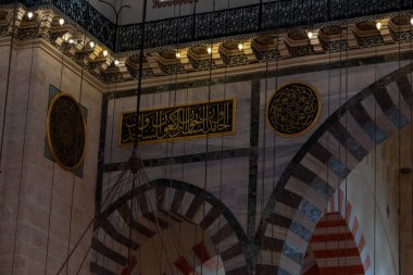 Süleyman Camii 'nin içi, camide yeşil plaka üzerine İslami metin, geçmişe dönük altın avize, İslam ve din kavramına yakın, seçici odak: Süleyman Camii, İstanbul, Türkiye