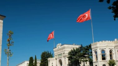 İstanbul Üniversitesi 'nin elinde iki Türkiye bayrağı, Türk ulusal bayrağı, rüzgarlı hava, Beyazit Meydanı' nda 4K 60 fps video, tarihi İstanbul Üniversitesi 'nin dışı, ünlü yapının girişi