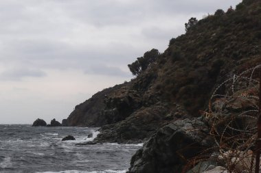 Kasvetli uçurumlar ve deniz, bulutlu manzara ve soğuk hava, gün batımına yakın zaman.