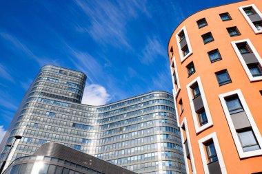 Viyana 'da modern sarayları olan şehir manzarası. Viyana sokaklarında güzel binalar, bir bina gri ve büyük cam pencereleri var, diğerinin turuncu duvarı var..