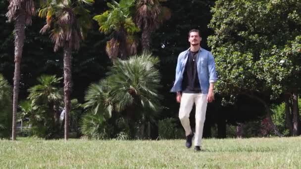 Νεαρός Μπλε Μάτια Περπατάει Στο Δημόσιο Πάρκο Φοράει Τζιν Πουκάμισο — Αρχείο Βίντεο