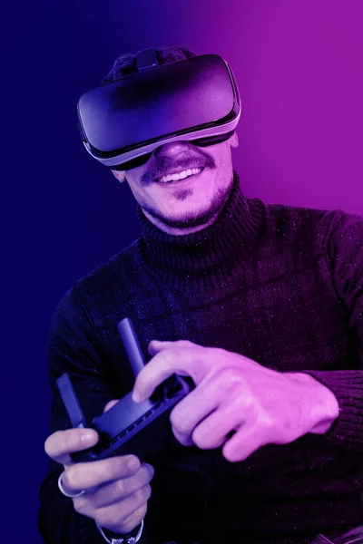 Young man is using virtual reality viewer. Portrait of modern man playing with a flight simulator.