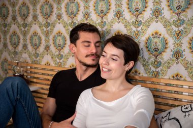 Young couple is sitting on the bed and kissing. Couple and love concept.