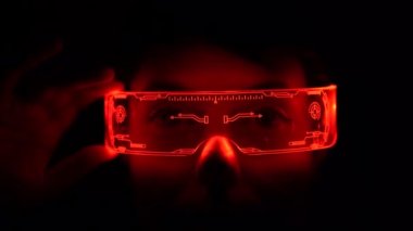 Young woman is using virtual reality glasses. Portrait of woman wearing backlit glasses while playing game.