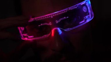 Young man is using virtual reality glasses. Portrait of man wearing backlit glasses while playing game.