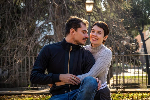这对年轻夫妇正坐在罗马的一条公园长椅上 这对年轻貌美的恋人正在拥抱 — 图库照片