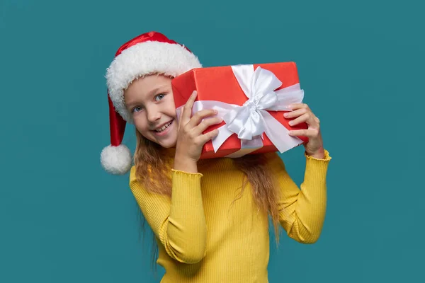 산타클로스 모자를 멋지게 아이는 청록색 배경에 상자를 있습니다 크리스마스를 준비하고 — 스톡 사진