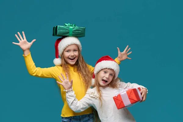 크리스마스 행사를 즐기는 어린이들 청록색 배경에 크리스마스 상자가 모자를 어린이들 — 스톡 사진