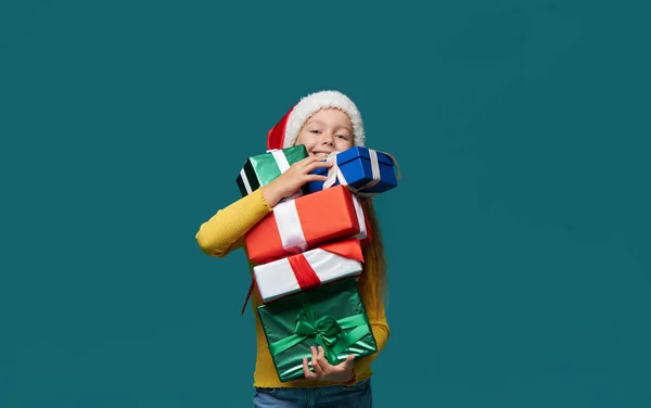 산타클로스 모자를 멋지게 아이는 청록색 배경에 상자를 있습니다 크리스마스를 준비하고 — 스톡 사진