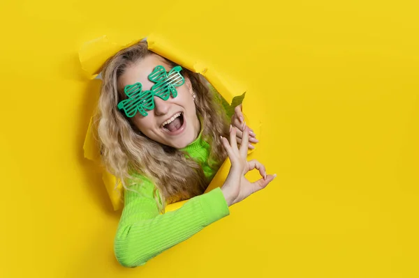 Meglepett Zöld Lóhere Alakú Szemüveget Visel Fényes Sárga Papírlyukon Keresztül — Stock Fotó