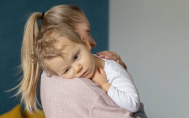 Cute little baby sleeps sweetly on mom's shoulder