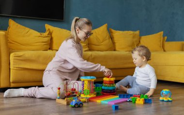 A young mother plays educational games with her baby at home on the floor