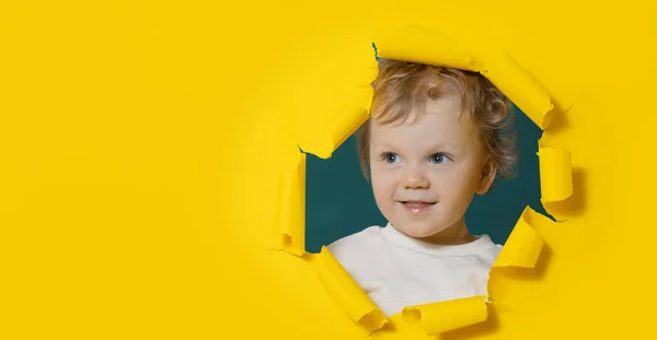 stock image Little surprised baby boy looking, peeping through the bright yellow paper hole. Advertise childrens goods. Happy childhood. Copy space for text.	