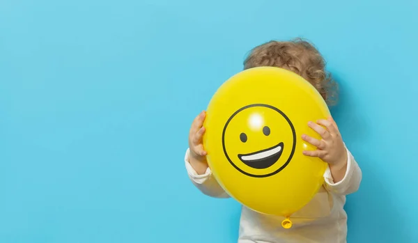 Söt Unge Blå Bakgrund Håller Gul Ballong Med Glad Emoji — Stockfoto