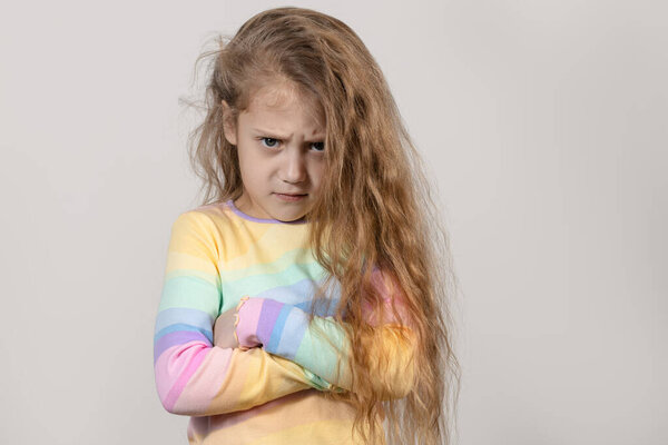 Cute upset little girl isolated on white background  grimacing at the camera. Arms folded across chest