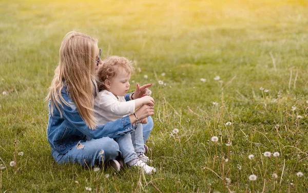 年轻的母亲和她的小儿子在公园里玩耍 蒲公英采花吹风 — 图库照片