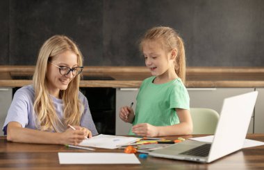 Alternatif Pedagoji. Genç bir bayan öğretmen, küçük bir kızla bireysel dersler veriyor. Bilgisayardan çevrimiçi dersler, uzaktan öğrenme dersleri. Bir çocukta yaratıcı becerilerin gelişimi
