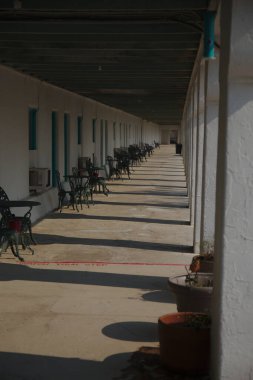 Amargosa Opera Binası 2015 'te Kaliforniya' da Ölüm Vadisi kavşağında. Gölgeler, masa ve sandalyelerle dolu uzun bir koridor boyunca sütunlar tarafından dökülür..