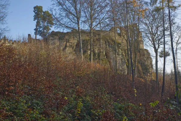 Ortaçağ şatosu sonbahar günü ağaçların arkasında, mavi gökyüzü ve renkli yapraklı ağaçlar.