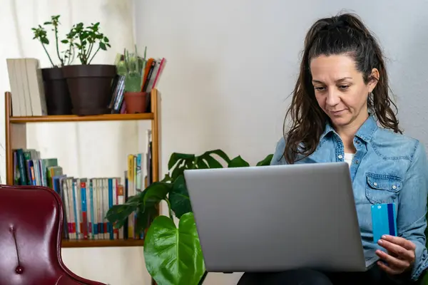 Yetişkin bir kadın, banka kartı ve bilgisayarla rahat bir çevre teknolojisinde alım yapıyor.