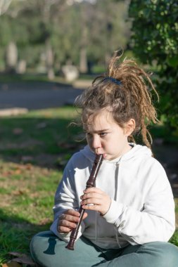 Müzikal Cazibe: Parkta Dreadlocks ve Flütü Olan Bir Çocuğun Dikey Portresi