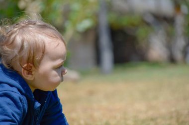 Sessiz yeşil parkta, 9 aylık bir bebek yeni renkler ve dokular keşfediyor..