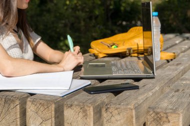 Sınıfın başında, kampüste notlar alan genç bir üniversiteli kız. Öğrenci elleri, dizüstü bilgisayar, akademik yaşam, teknoloji, eğitim ortamı