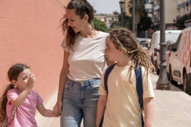 Genç anne güneşli bir günde oğlunu ve kızını okula götürür. Okula, okula, sırt çantalarına, ailene, gülümsemene, okula giderken..