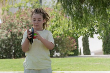 Rastalı çocuk güneşli bir parkta cırt cırtlı top oynamaktan hoşlanıyor. Yakından çekilirken neşe ve konsantrasyon gösteriyor. Yeşil çimenler ve doğal çevre rahatlatıcı bir atmosfer yaratıyor..