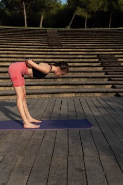 Genç ve güzel bir kadın sabah plajda akroyoga yapıyor.