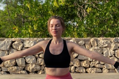 Kadın dışarıda esneme egzersizi yapıyor.