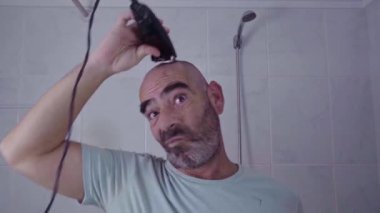 Bir adam ev ortamında yakalanır, kafasını traş eder ve elektrikli makineyle temiz bir kesim yapar..