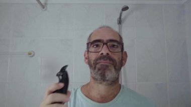 Evde kafasını tıraş eden bir adam, tıraş bıçağını banyoda kendi kendine temizlenmiş bir saç kesimi için kullanır..