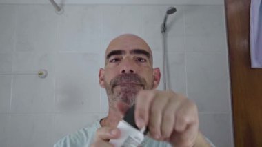 Kel ve yetişkin bir adam evdeki banyosuna deodorant sürüyor. Temizlik rutinini tamamlarken mutlu ve mutlu görünüyor. Taze bir his ve temiz bir kokunun tadını çıkarıyor..