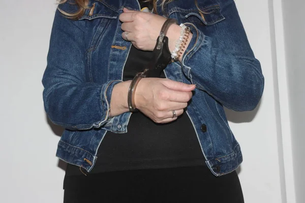 A closeup of the handcuffs on an arrested woman. The prisoner is handcuffed and awaiting transport to jail.