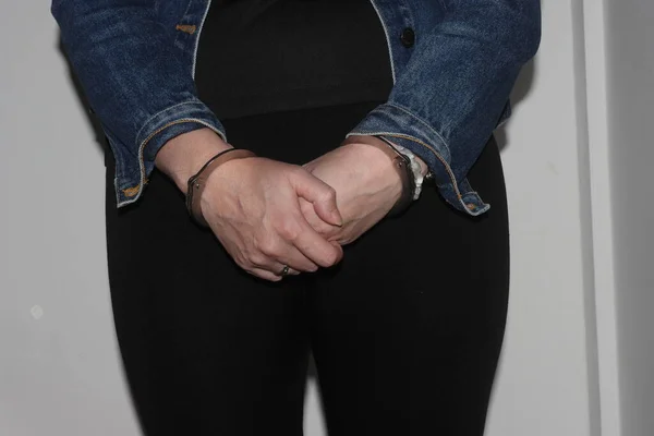 A closeup of the handcuffs on an arrested woman. The prisoner is handcuffed and awaiting transport to jail.