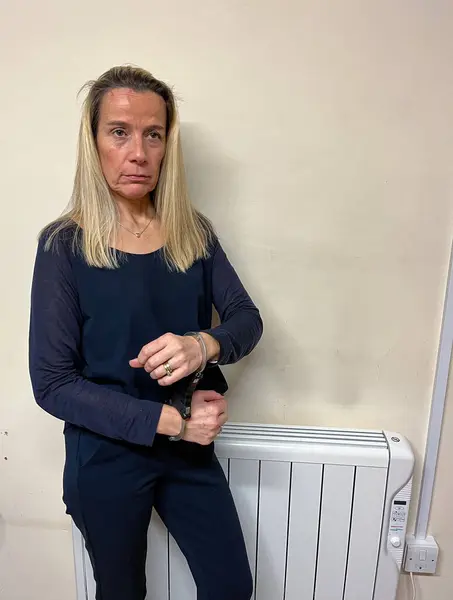 stock image A woman is handcuffed after being arrested. Her handcuffs are in a front stacked position.