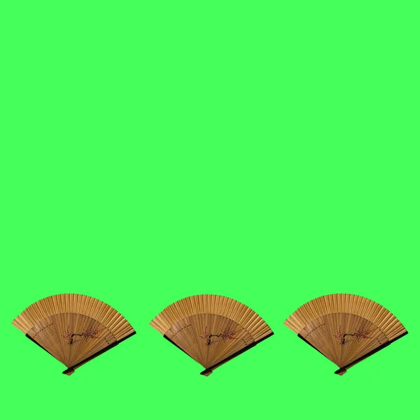 Three wooden an elegant fans with fine patterns on an green background.. Flat lay concept.