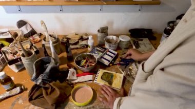 Genç Latin kadın, kendi resim ve heykel stüdyosunda farklı sanatsal tekniklerle resimler yapıyor.