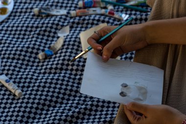 Piknik tarihlerinde akordelalarla boyanmış, fırça kullanan ve Meksika Guadalajara Latin Amerika kağıdına resim çizen genç bir kadın.