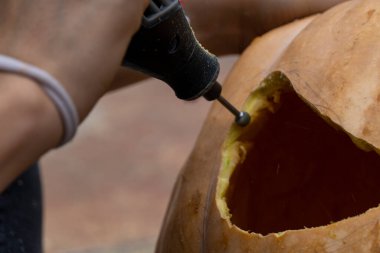 Meksika Latin Amerika Cadılar Bayramı için balkabağı delen matkaplı genç bir adam.