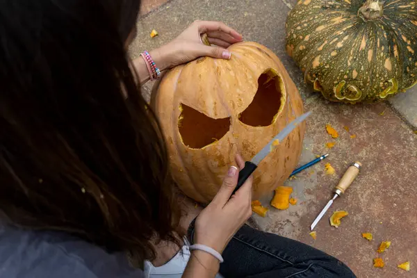 Vrouw Snijden Grote Oranje Pompoen Voor Halloween Feest Terwijl Zitten — Stockfoto