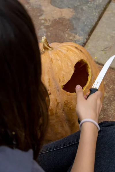 Самка Вырезает Большую Оранжевую Тыкву Хэллоуина Сидя Дома Деревянным Столом — стоковое фото