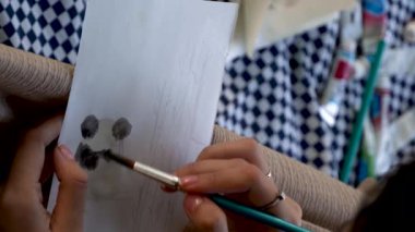 Piknik tarihlerinde akordelalarla boyanmış, fırça kullanan ve Meksika Guadalajara Latin Amerika kağıdına resim çizen genç bir kadın.