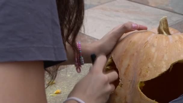 Самка Вырезает Большую Оранжевую Тыкву Хэллоуина Сидя Дома Деревянным Столом — стоковое видео